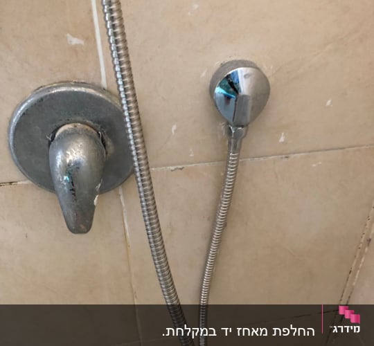 ברז מקלחת עם צינור מתכת על קיר קרמיקה